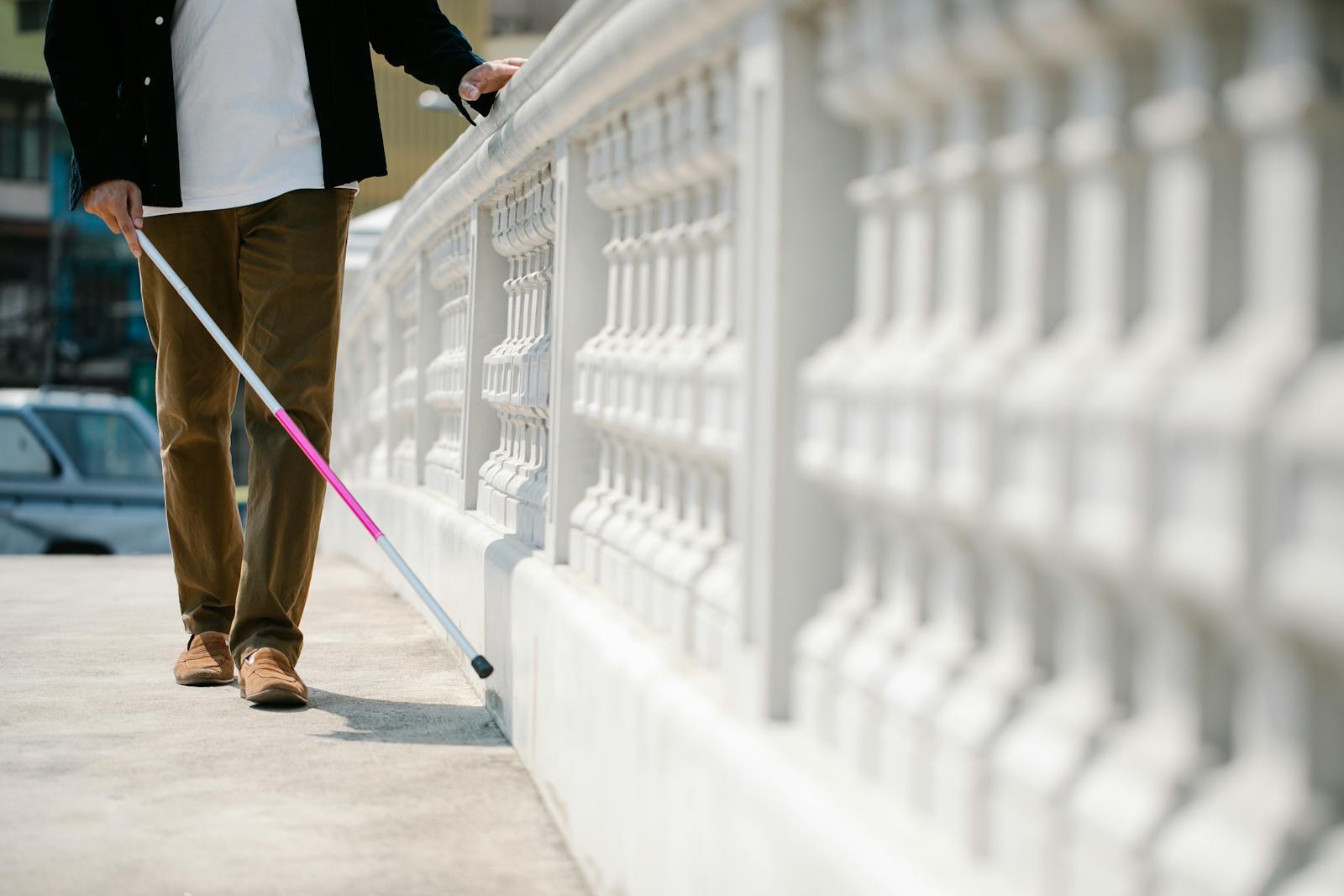 A visually impaired individual confidently walks outdoors with a cane.